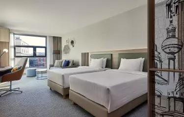 Hotelzimmer mit zwei Einzelbetten, einem Schreibtisch und einem Sitzbereich mit Sofa