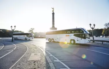 Zwei Busse von Bus Verkehr Berlin fahren durch Berlin, im Hintergrund die Siegessäule.