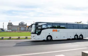 Ein BVB.net Reisebus fährt im Vordergrund auf der Straße, im Hintergrund der Reichstag in Berlin.