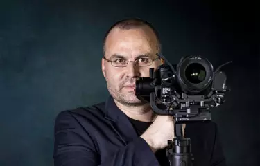 Der Gottwald guckt professionell in die Kamera, mit seiner Kamera, an dieser vorbei.