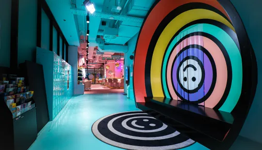 Bunter, moderner Eingang zum Upside-Down-Erlebnis mit Regenbogenkreisen und einem Upside-Down-Teppich.