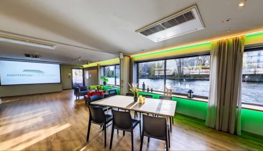 Heller Konferenzraum mit Blick auf einen Fluss, moderne Einrichtung und große Fenster.