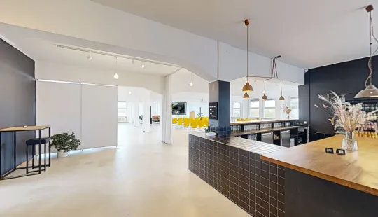 Moderne, helle Büro-Lounge mit Theke, Barhockern und dekorativen Lampen.