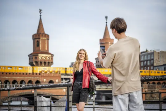 Young couple taking selfies on the Oberbaum Bridge with the S-Bahn in the background