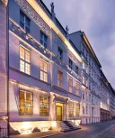 Historische Hausfassade bei Dämmerung, beleuchtet, mit Verzierungen und großen Fenstern