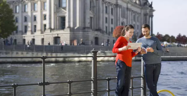 Touristen mit Stadtplan vor dem Spreeufer mit Blick auf den Berliner Reichstag