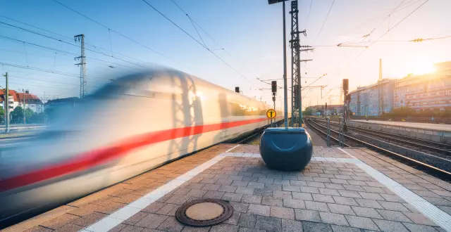 White high speed train in motion on the railway station at sunset. Germany. Blurred modern intercity train on the railway platform. Industry. Passenger train on railroad. Railway travel in Europe