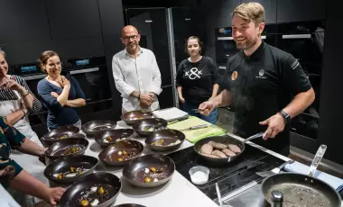Koch steht vor Menschen und gibt Workshop in einer Küche