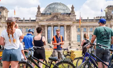 Eine Gruppe von Fahrrad-Nutzenden steht vor dem Berliner Reichtstag 