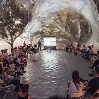 Gäste sitzen im Kreis in der Blase des Spacebuster Berlin und hören einem Vortragenden zu