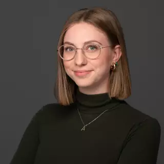 Junge Frau mit kurzen Haaren und Brille mit grünem Rollkragenpullover