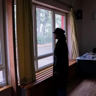 Frau steht vor Fensterscheibe und schaut nach draußen