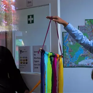 Mitarbeiterin Mehrgenerationshaus zeigt Besucherin Stoffkunstwerk