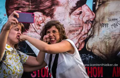 Zwei Mädchen machen Selfies vor der Berliner Mauer