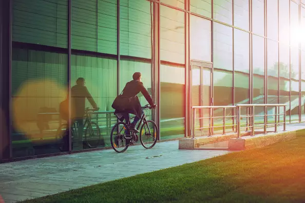Handsome man riding bicycle beside the modern office building