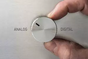 Finger dreht den Schalter von digital zu analog