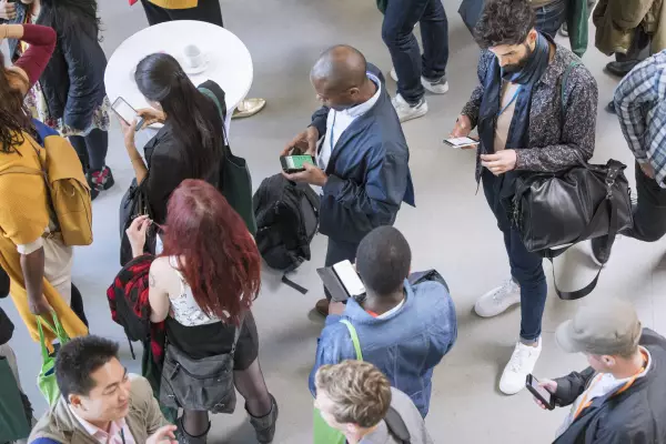 Businessleute benutzen ihr Smartphone bei einer Konferenz um Nachrichten zu erhalten