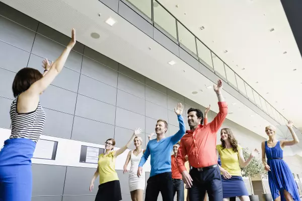 Business Leute tanzen zum Warm-Up im Büro mit einem Moderator