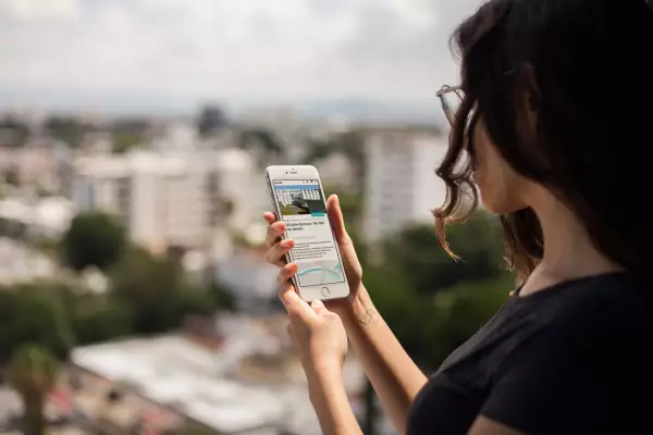 Woman looks at her smartphone with mobile app "100 years Bauhaus"