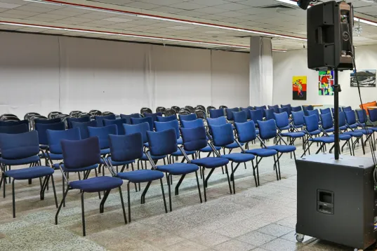 Reihen leerer blauer Stühle vor einer Bühne in einem Veranstaltungsraum