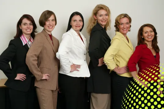 Sechs Frauen in Businesskleidung stehen nebeneinander und lächeln.