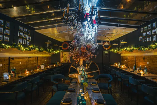 Stimmungsvoll beleuchtetes Restaurant mit festlich gedeckten Tischen und Kronleuchter.