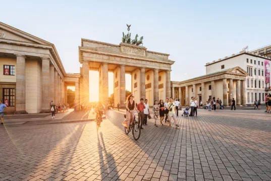 Menschen und Fahrräder vor dem Brandenburger Tor bei Sonnenuntergang