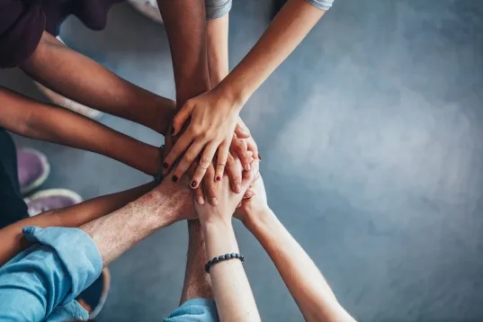 Close up top view of young people putting their hands together. Friends with stack of hands showing unity.
