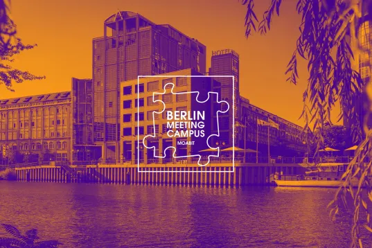 Spree riverbank in Berlin-Moabit with modern buildings and Berlin Meeting Campus logo