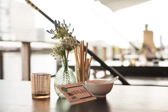 Nahaufnahme eines dekorierten Tisches mit einer Vase, Besteck und Schalen in einem modernen Restaurantambiente