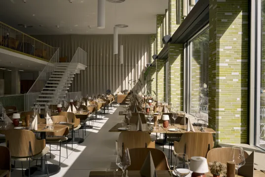 Helles modernes Restaurant mit großen Fenstern und eingedeckten Tischen.