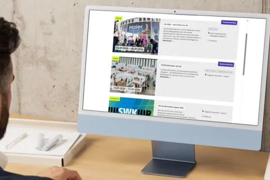 Man looking at event listings on a computer monitor in an office setting.