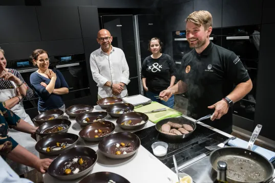 Koch steht vor Menschen und gibt Workshop in einer Küche