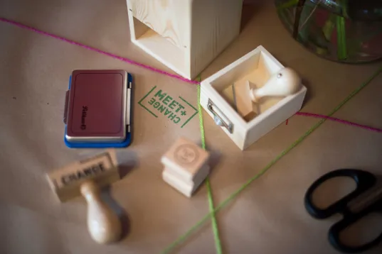 MEET & CHANGE work materials on a table, including several stamps, ink pads and small wooden boxes.