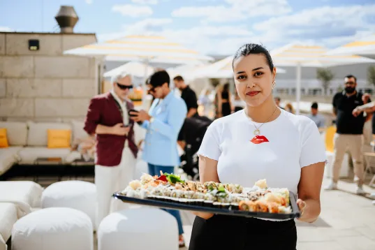 Service employee holding a tray on a roof terrace