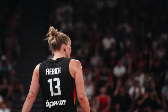 Basketballspielerin im schwarzen Trikot mit der Nummer 13, Publikum im Hintergrund.