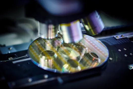Microscope lenses magnify a silicon wafer with electronic circuits in a laboratory.