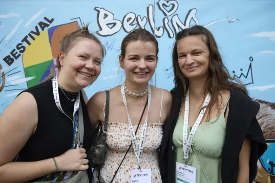 Three young women smile at the camera.