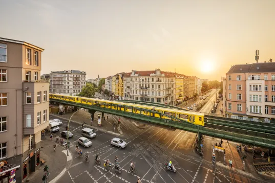 View of Eberswalder railway station with an S-Bahn train and cyclists and cars on the road