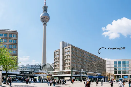 Berliner Fernsehturm und Alexanderplatz bei sonnigem Wetter, viele Menschen unterwegs.