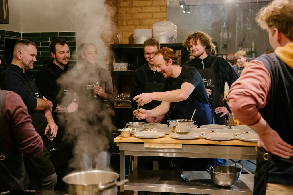 Group of chefs laughing while preparing food in a kitchen.